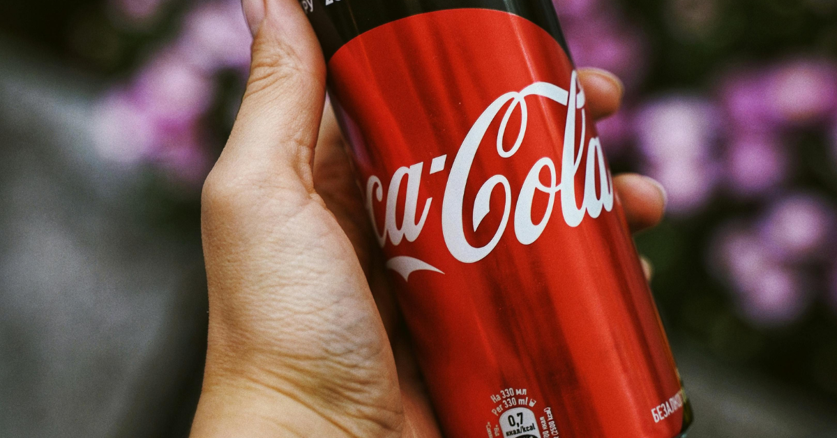 A hand holding a can of Coca Cola